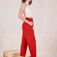 Side view of Heavyweight Trousers in Mustang Red and vintage off-white Sleeveless Turtleneck worn by Alex