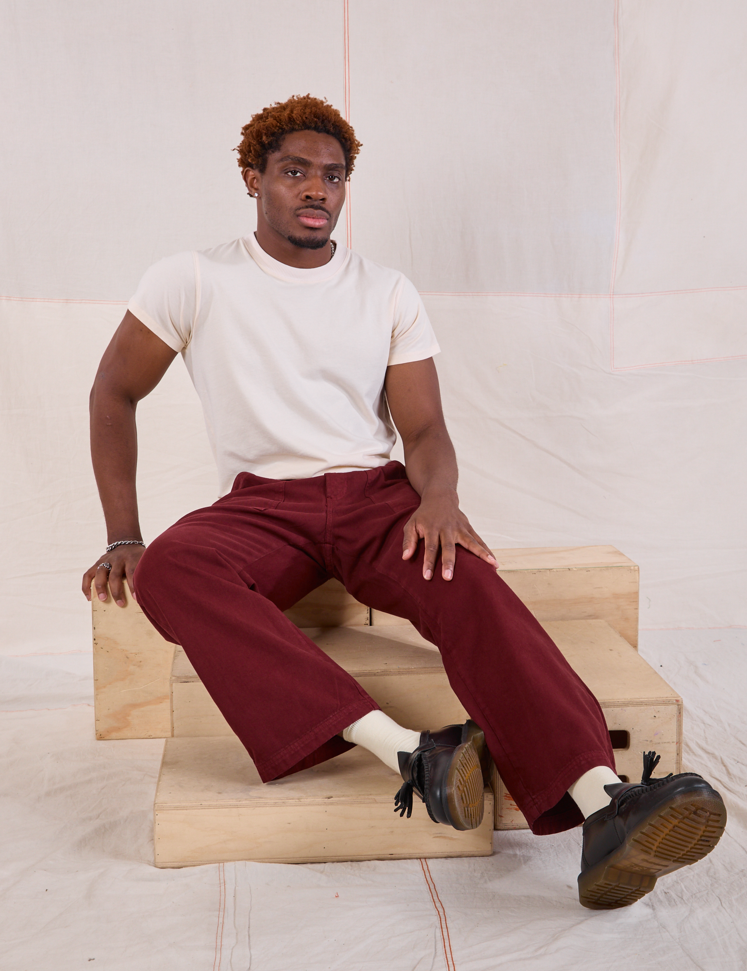 Issac is wearing Mid-Rise Work Pants in Red Wine and Organic Vintage Tee in vintage tee off-white