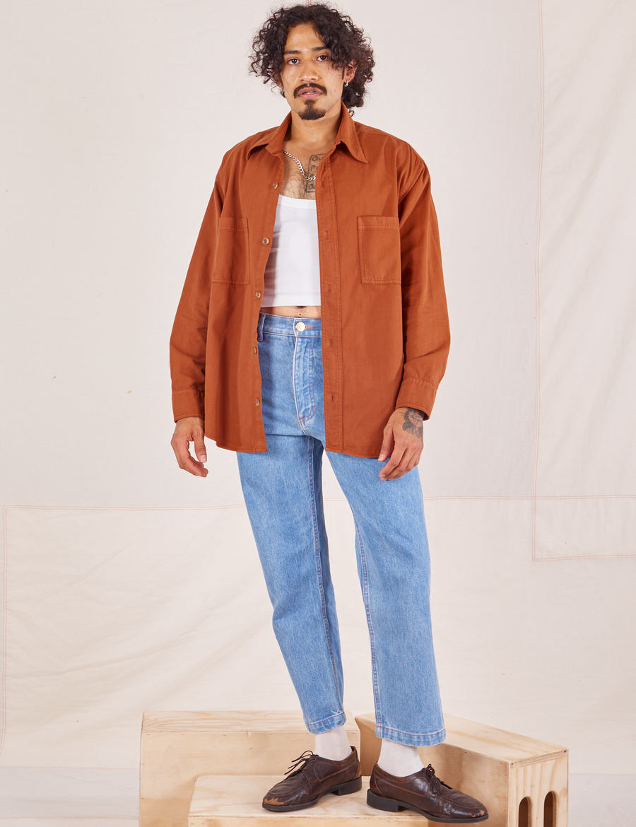 Jesse is wearing Oversize Overshirt in Burnt Terracotta paired with vintage off-white Tank Top and light wash Frontier Jeans