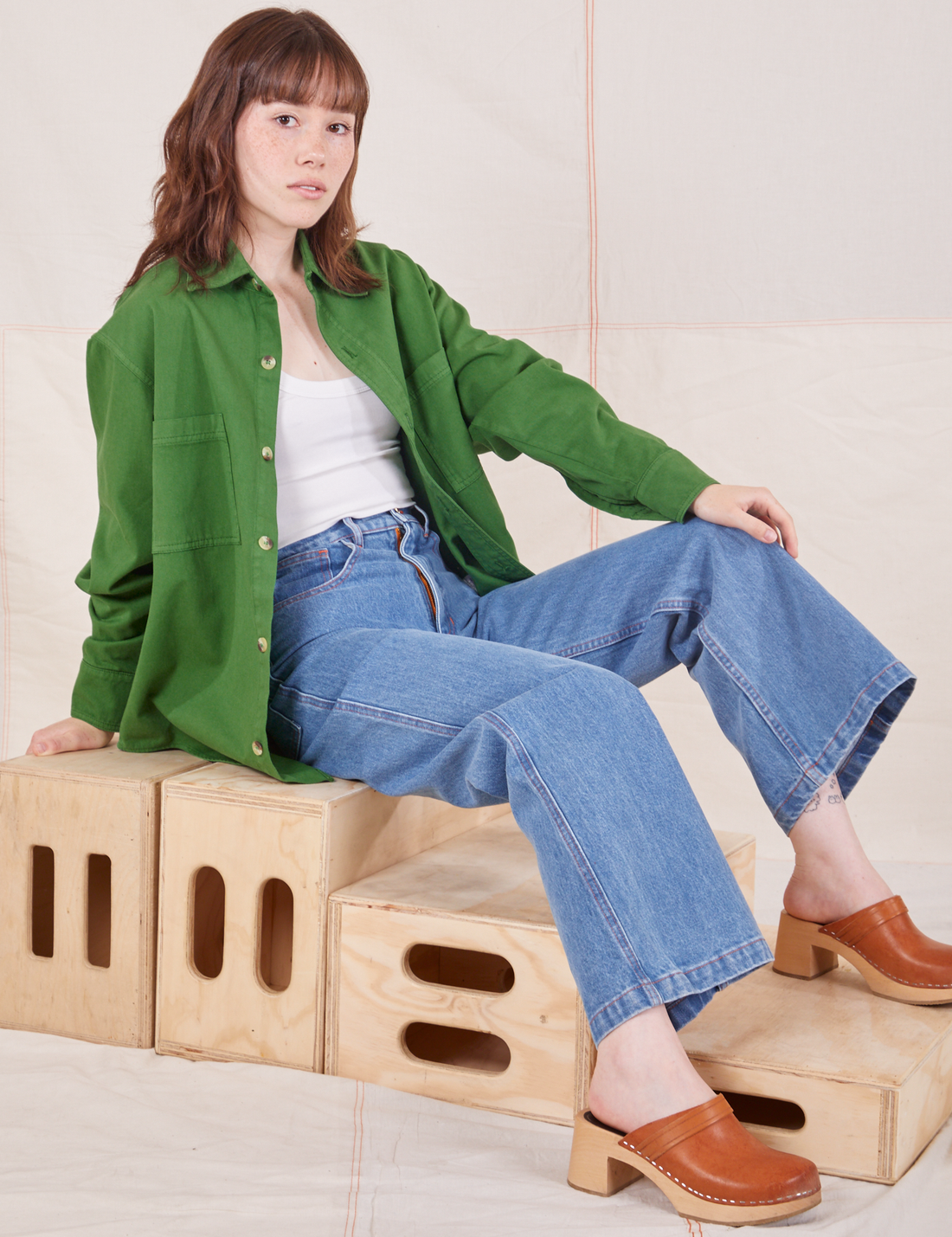 Hana is wearing Oversize Overshirt in Lawn Green, vintage off-white Cropped Tank Top and light wash Sailor Jeans