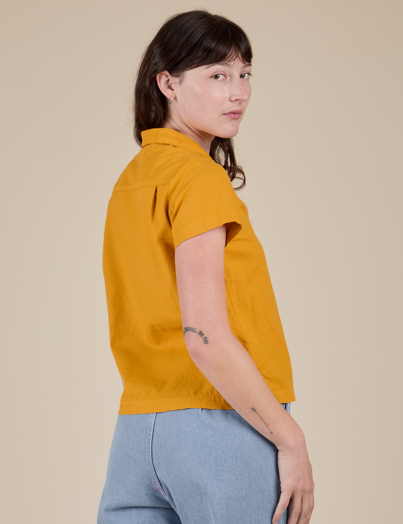 Angled back view of Pantry Button-Up in Mustard Yellow on Alex