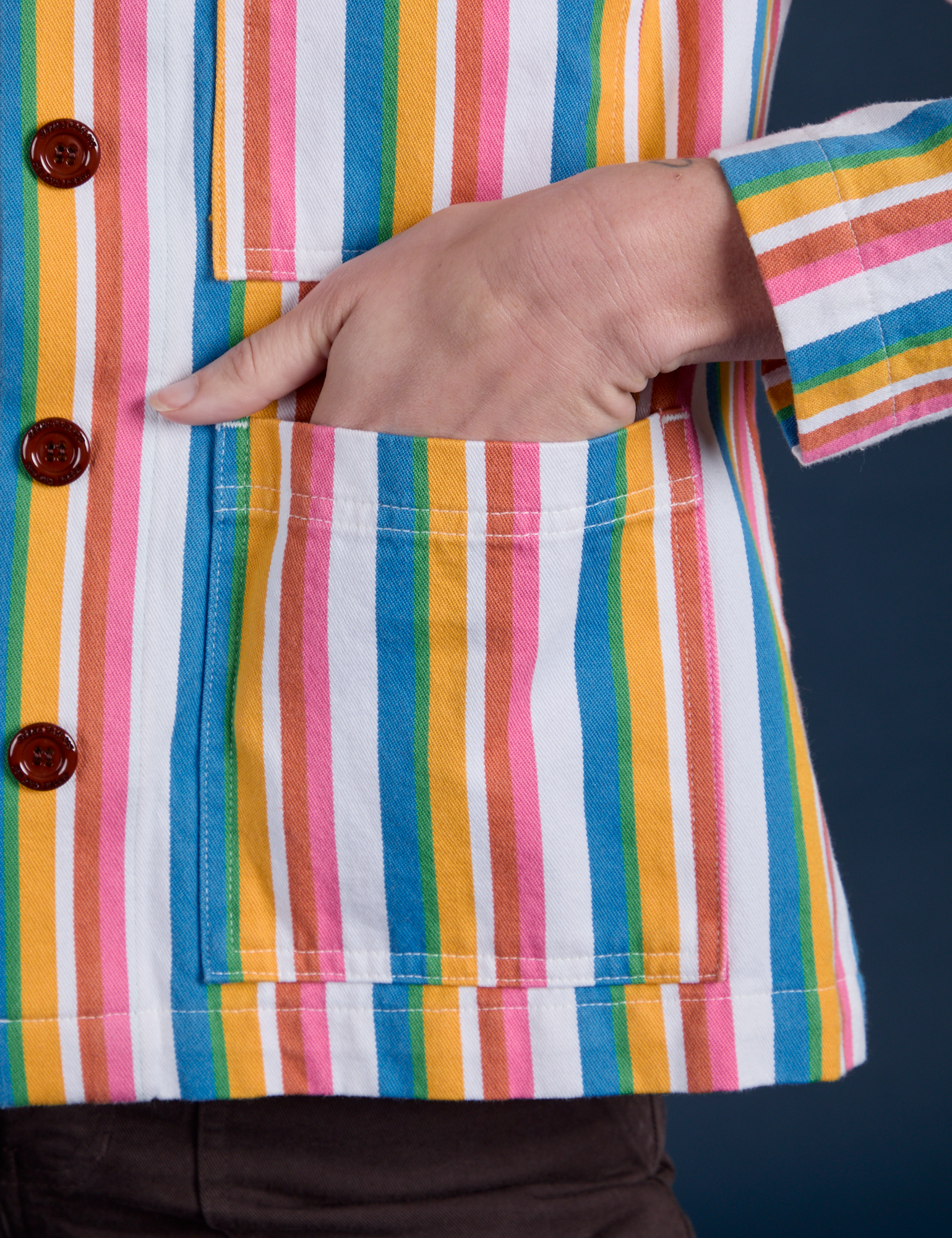Close up of Alex's hand in the front pocket of Stripe Work Jacket in Rainbow Stripe 