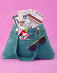 Overall Handbag in Marine Blue. Magic Kingdom brochures inside main compartment. Disney gift card in front pocket and sunglasses