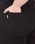 Petite Bell Bottoms in Basic Black back pocket close up. Ashley has her hand in the pocket.
