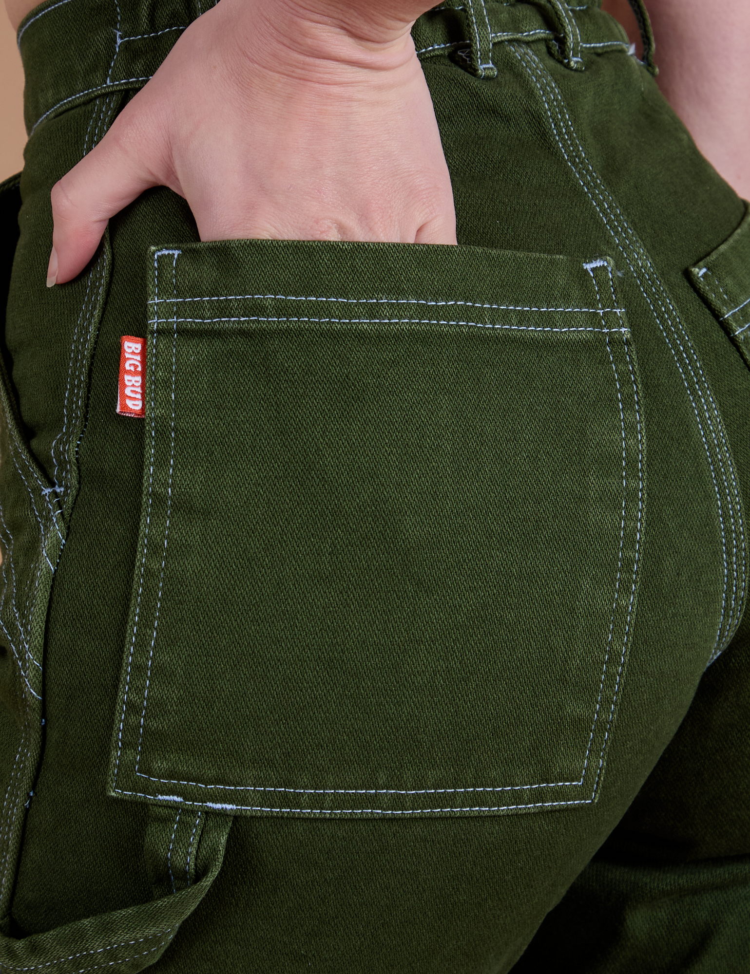 Close up of Alex's hand in the back pocket of Carpenter Jeans in Evergreen