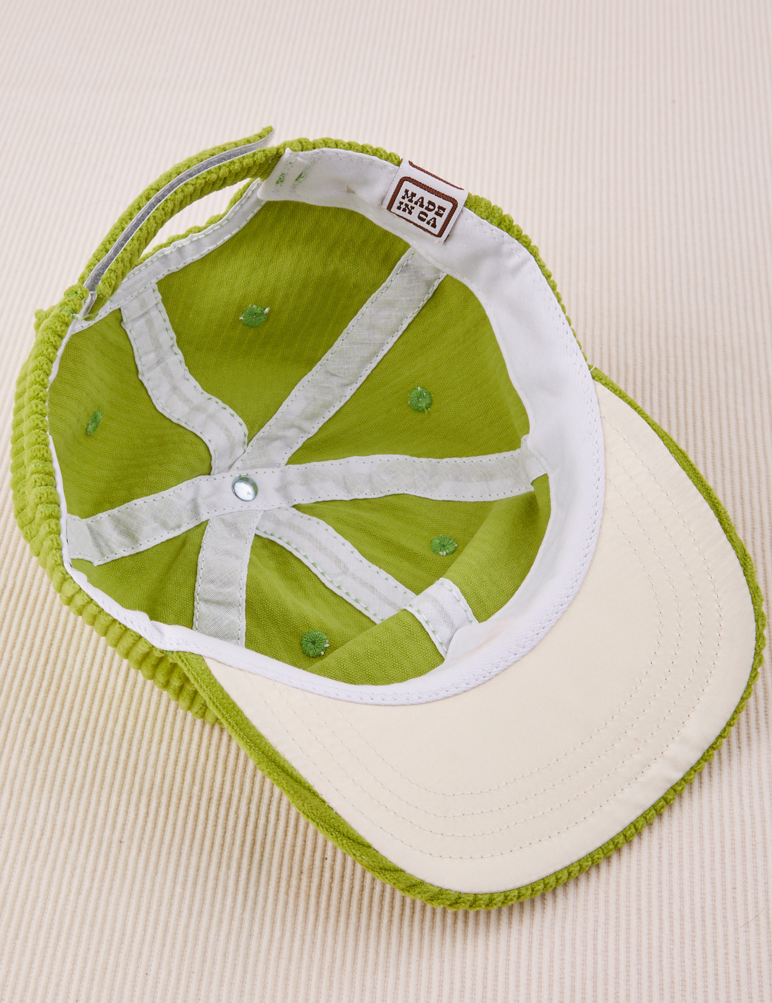 Dugout Corduroy Hat in Gross Green flipped over. White satin under-bill