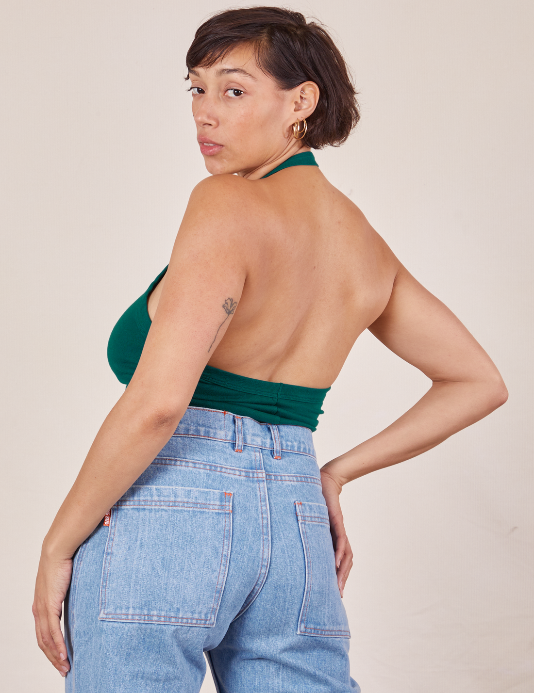 Back view of Halter Top in Hunter Green and light wash Sailor Jeans worn by Tiara