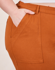 Petite Pencil Pants in Burnt Terracotta front pocket close up. Ashley has her hand in the pocket.