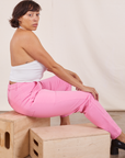 Side view of Pencil Pants in Bubblegum Pink on Tiara. She is sitting on a wooden crate.
