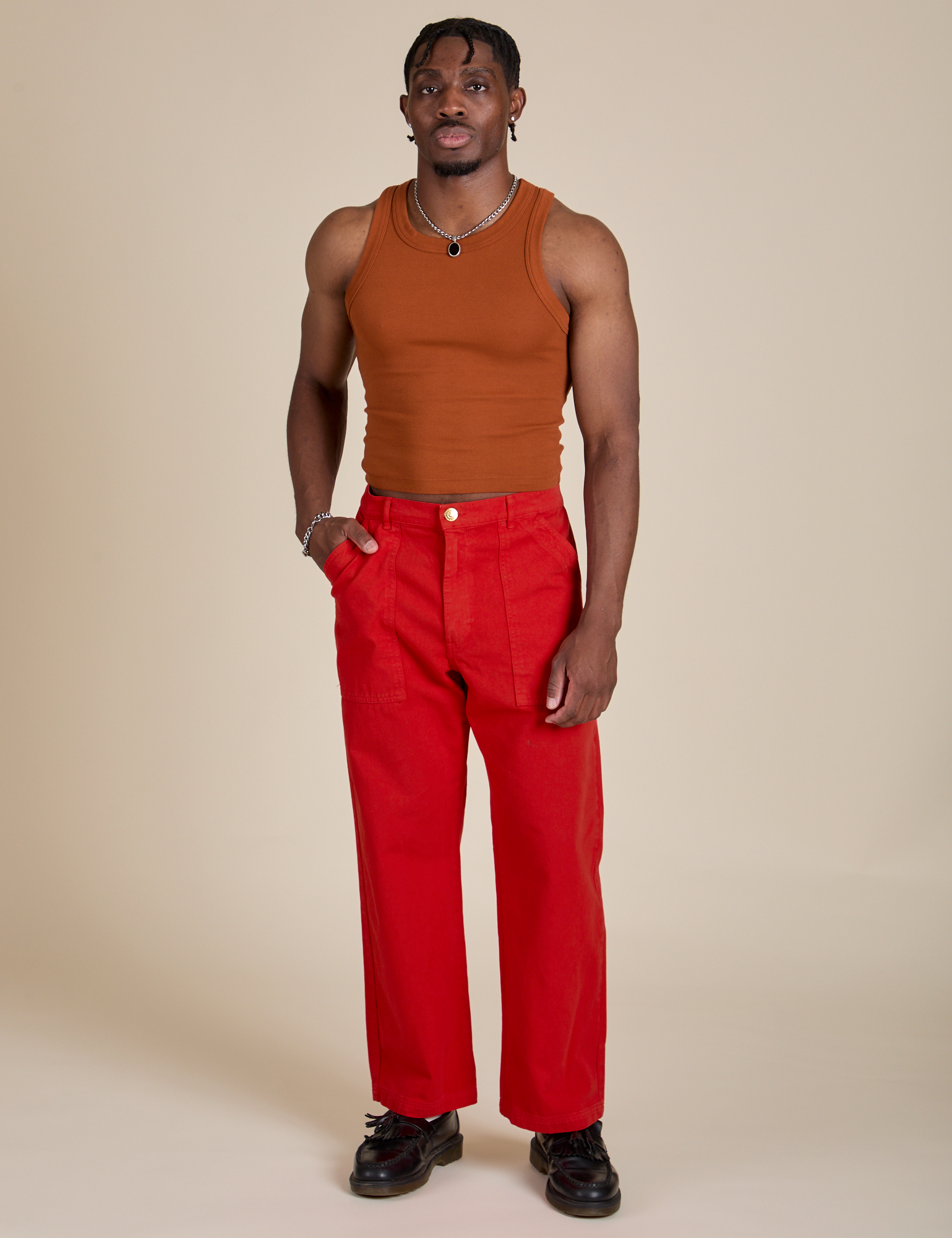 Isaac is wearing Racerback Tank in Burnt Terracotta and mustang red Work Pants