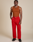 Isaac is wearing Racerback Tank in Burnt Terracotta and mustang red Work Pants