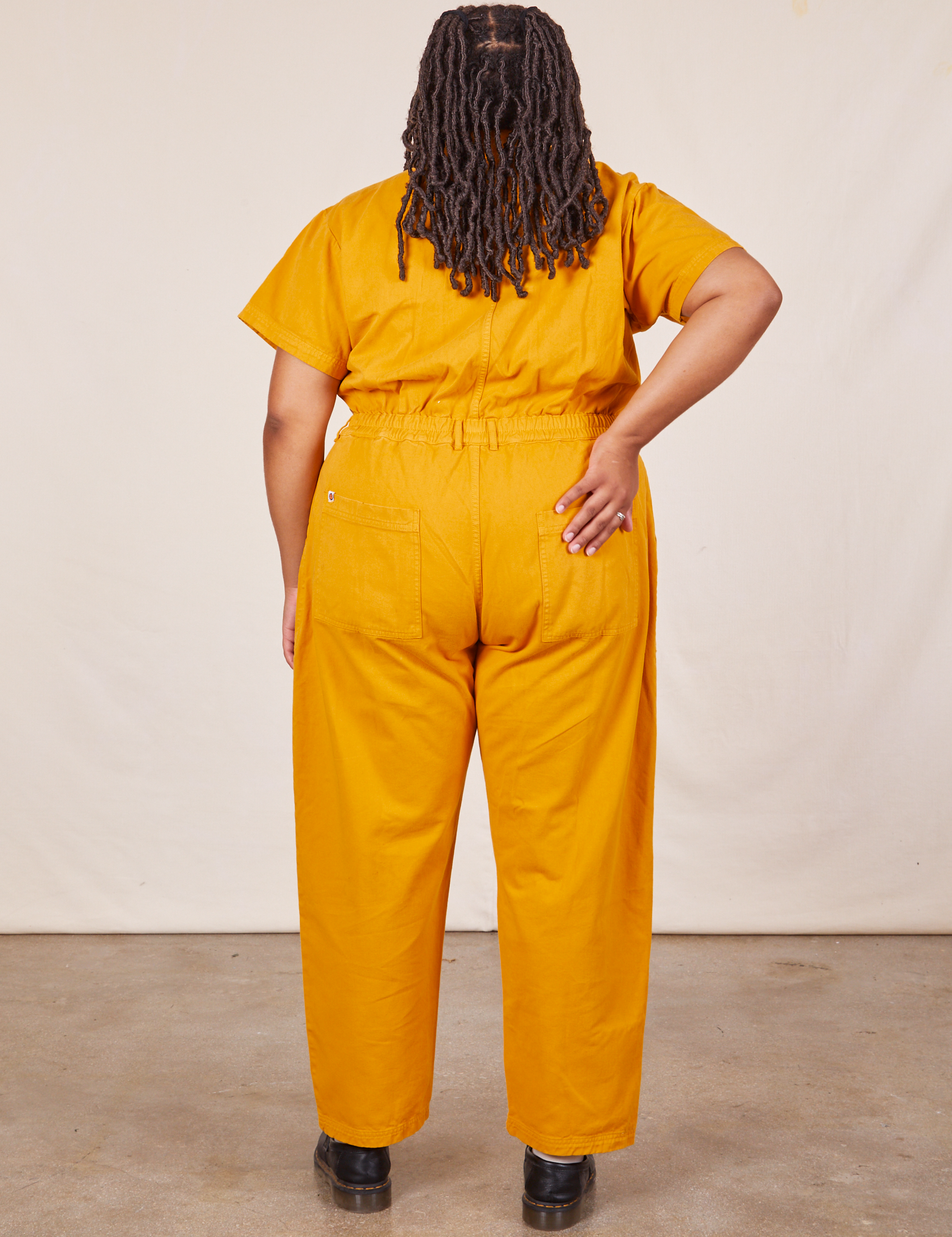 Back view of Short Sleeve Jumpsuit in Mustard Yellow worn by Alicia