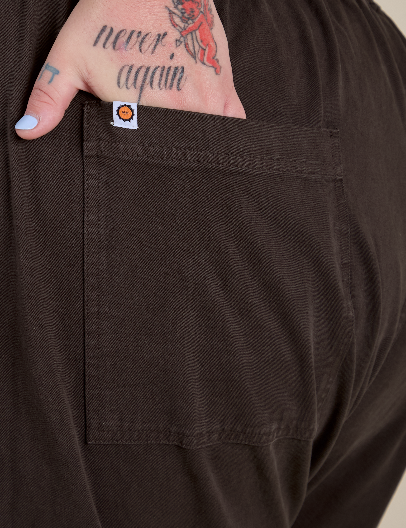 Close up of Sam's hand in the back pocket of Short Sleeve Jumpsuit in Espresso Brown
