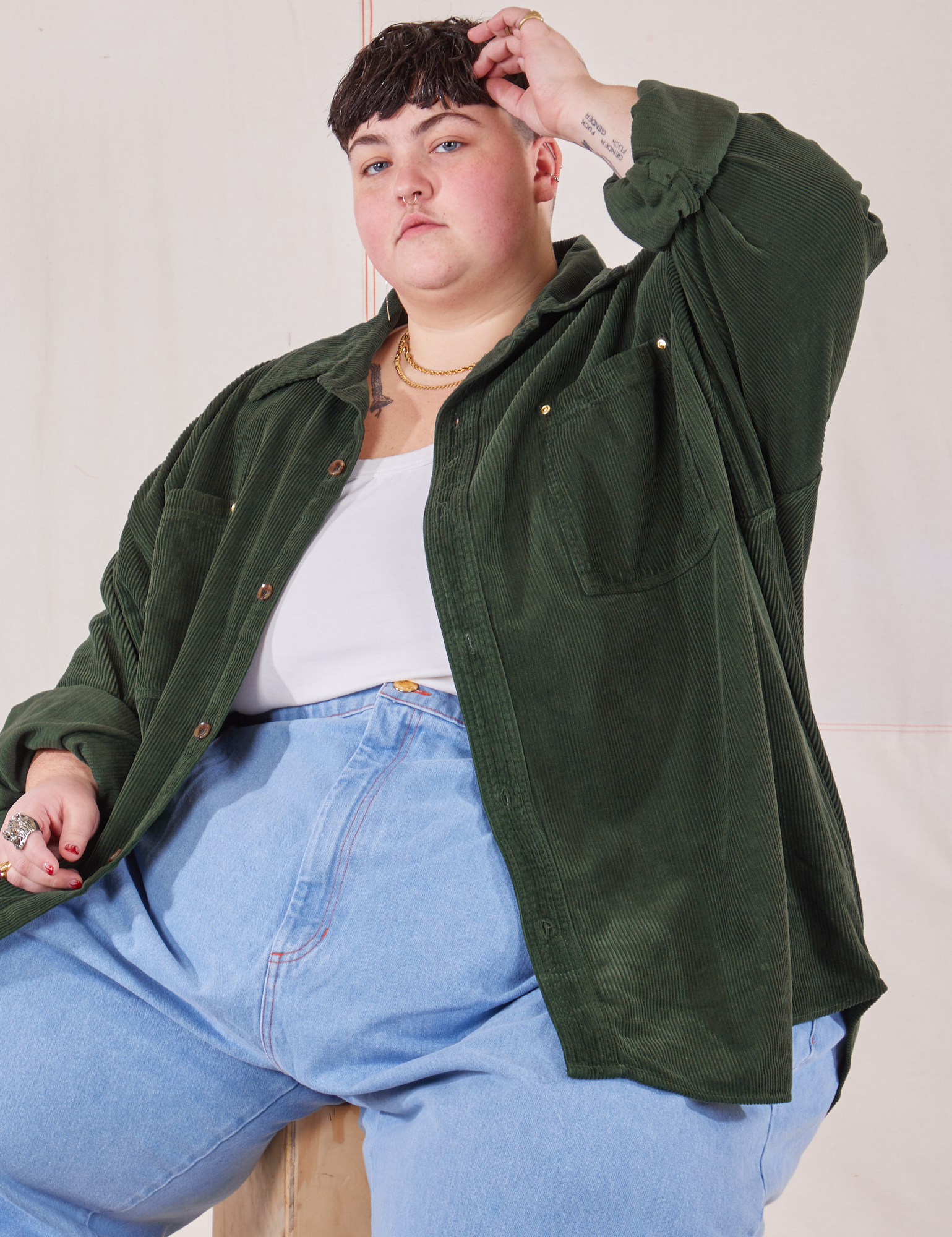 Jordan is wearing Corduroy Overshirt in Swamp Green and light wash Trouser Jeans
