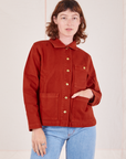 Alex is wearing a buttoned up Denim Work Jacket in Paprika with her left hand in the pocket.