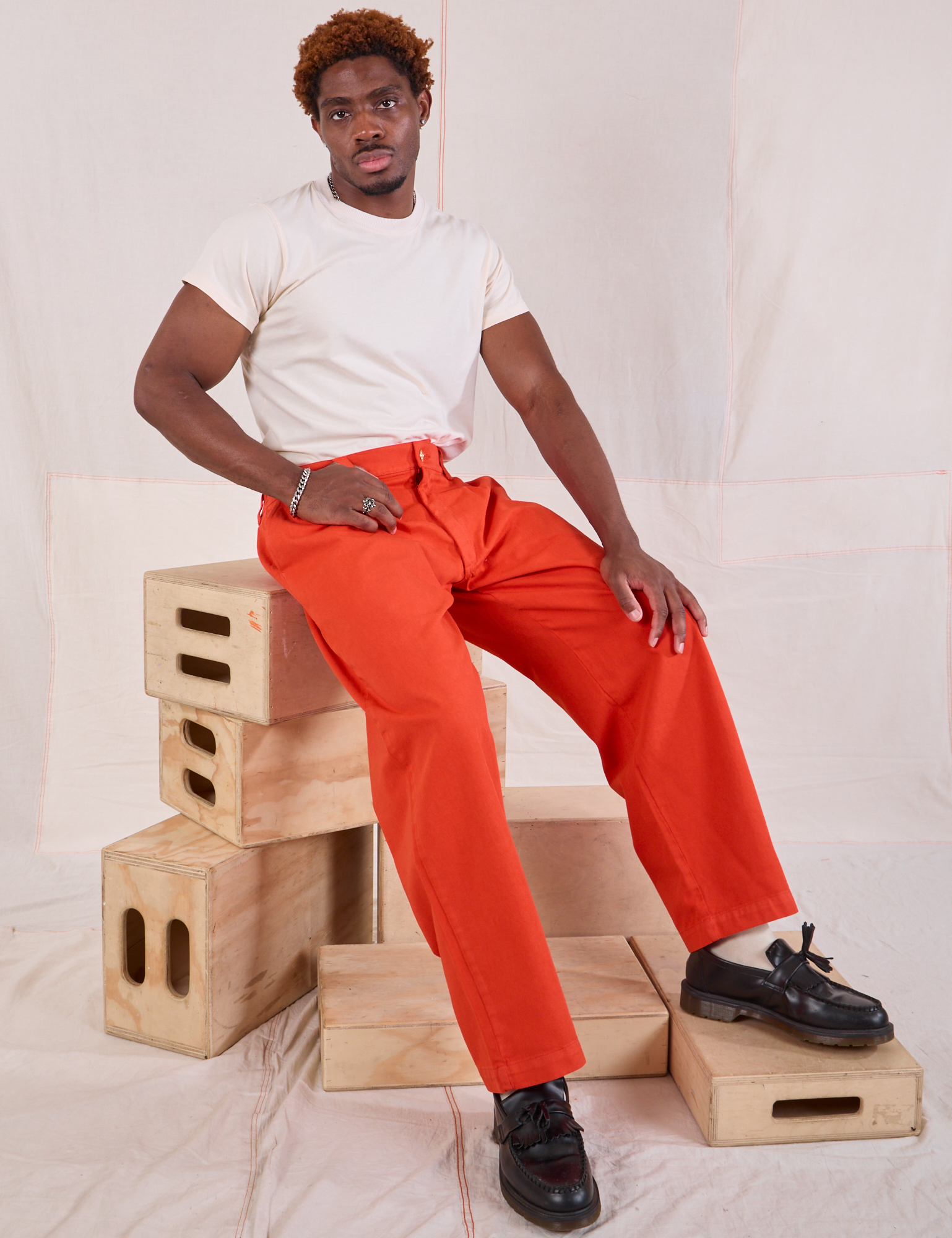 Issac is wearing Mid-Rise Pleated Trousers in Chili Red and Organic Vintage Tee in vintage tee off-white