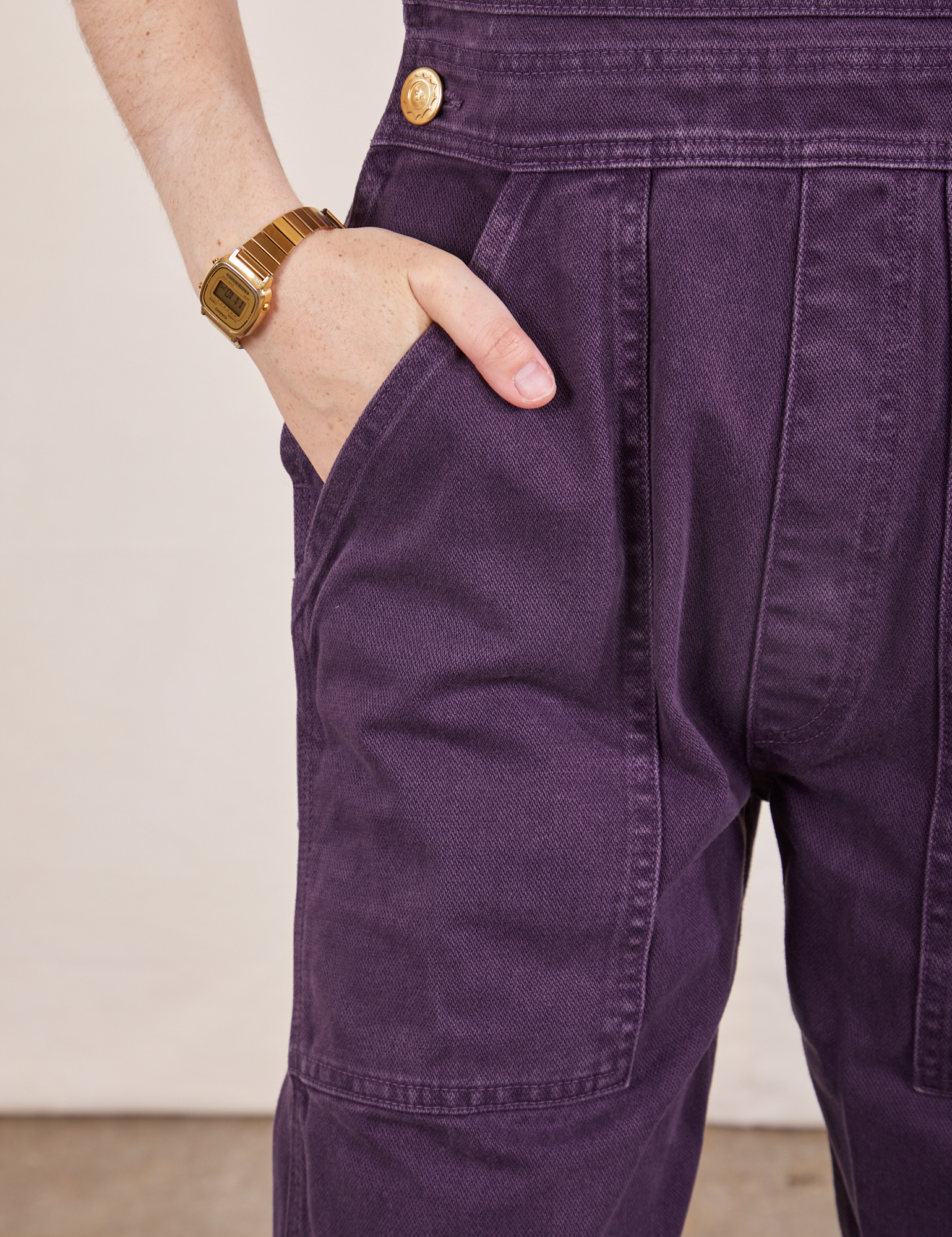 Front pocket close up of Original Overalls in Mono Nebula Purple. Hana has her hand in the pocket.