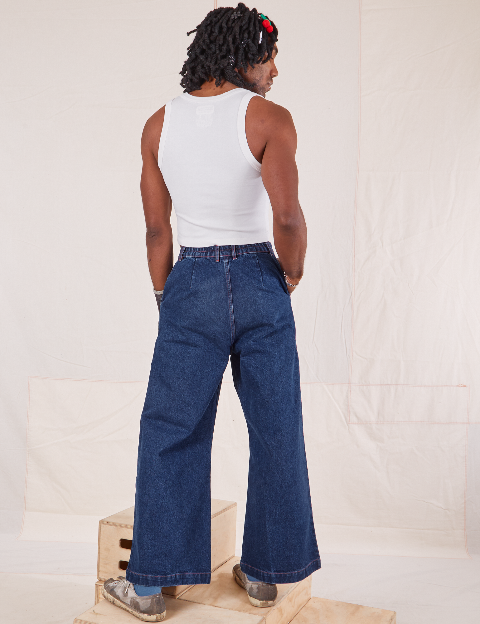 Back view of Indigo Wide Leg Trousers in Dark Wash and vintage off-white Tank Top on Jerrod