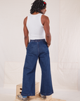 Back view of Indigo Wide Leg Trousers in Dark Wash and vintage off-white Tank Top on Jerrod