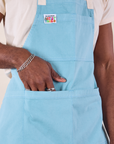 Front close up of Full Denim Apron in Baby Blue with Jerrod's hand in a pocket