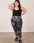 Ashley is 5'7" and wearing 1XL Petite Black Magic Waters Work Pants paired with black Cropped Cami