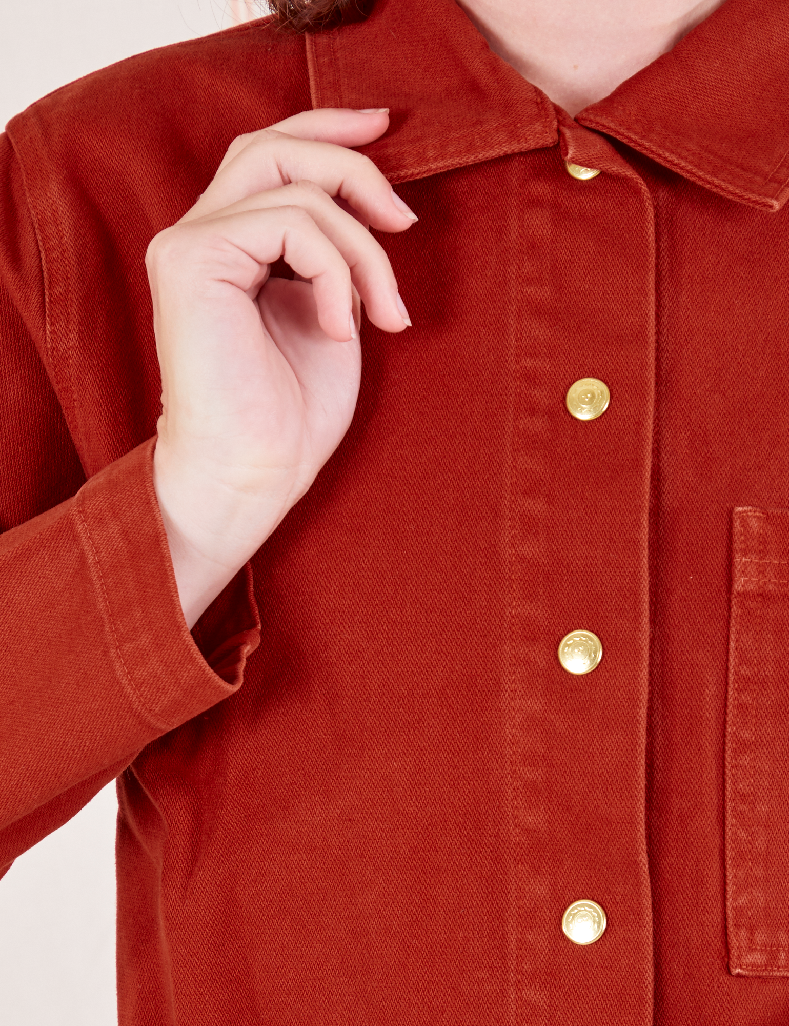 Front close up of Denim Work Jacket in Paprika worn by Alex. Brass button closures down the front of the jacket.