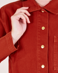 Front close up of Denim Work Jacket in Paprika worn by Alex. Brass button closures down the front of the jacket.
