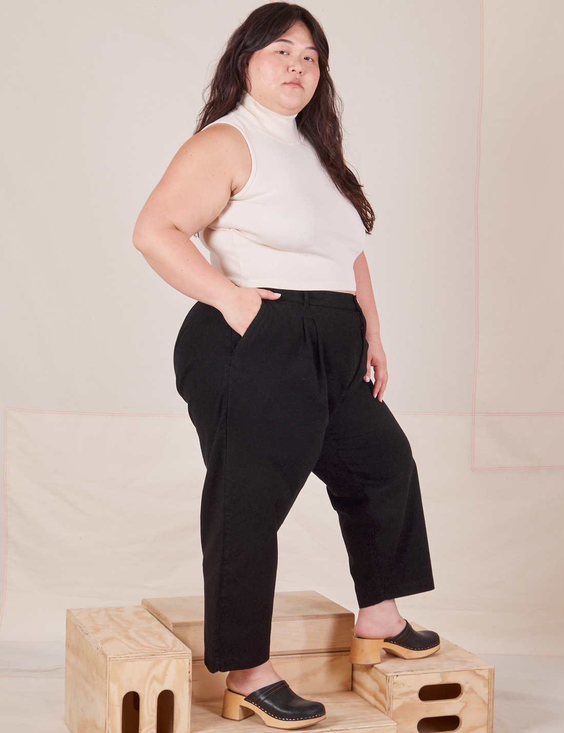 Side view of Heavyweight Trousers in Basic Black and vintage off-white Sleeveless Turtleneck worn by Ashley.