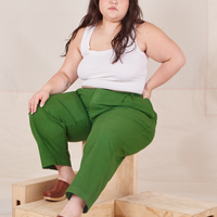 Ashley is sitting on a wooden crate wearing Heavyweight Trousers in Lawn Green and vintage off-white Cropped Tank Top