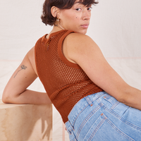 Tiara is sitting on a wooden crate with her back turned. She is wearing Mesh Tank Top in Burnt Terracotta.
