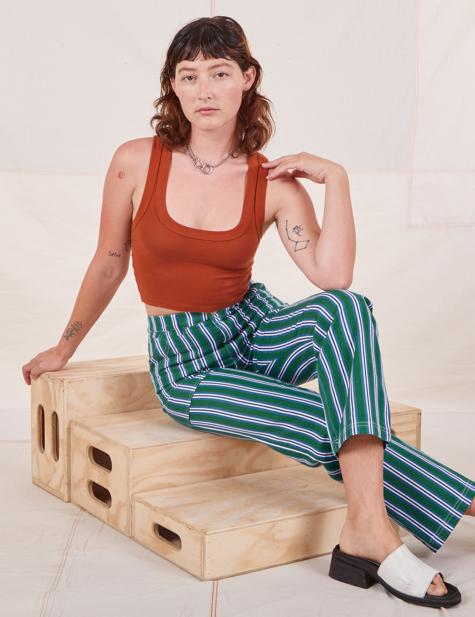 Alex is wearing Stripe Work Pants in Green and burnt terracotta Cropped Tank Top