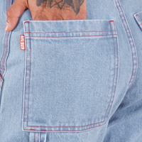 Back pocket close up of Carpenter Jeans in Light Wash. Jesse has their hand in the pocket.