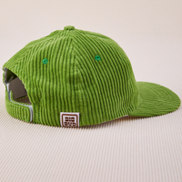 Side view of Dugout Corduroy Hat in Bright Olive. Big Bud label sewn on edge of hat.