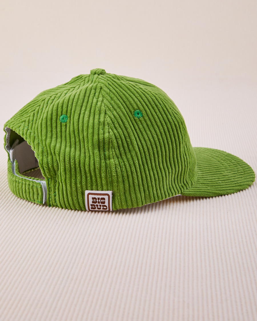 Side view of Dugout Corduroy Hat in Bright Olive. Big Bud label sewn on edge of hat.