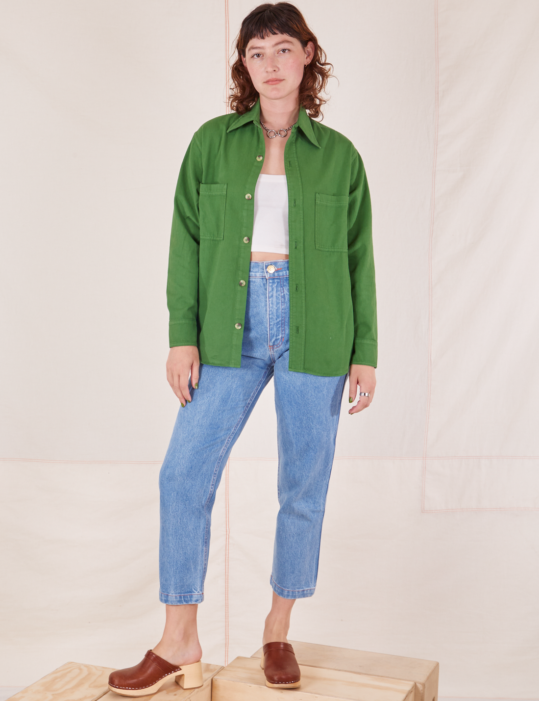 Alex is wearing Oversize Overshirt in Lawn Green, vintage off-white Tank Top and light wash Frontier Jeans