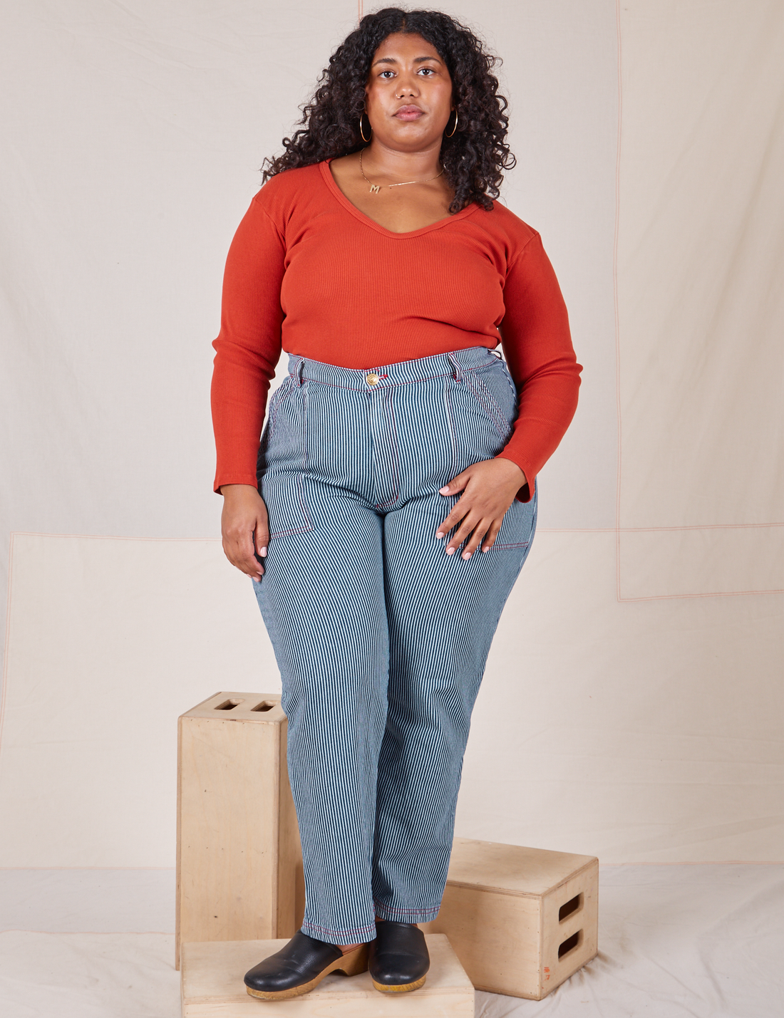 Morgan is 5'5" and wearing 1XL Railroad Stripe Denim Work Pants paired with a paprika Long Sleeve V-Neck Tee