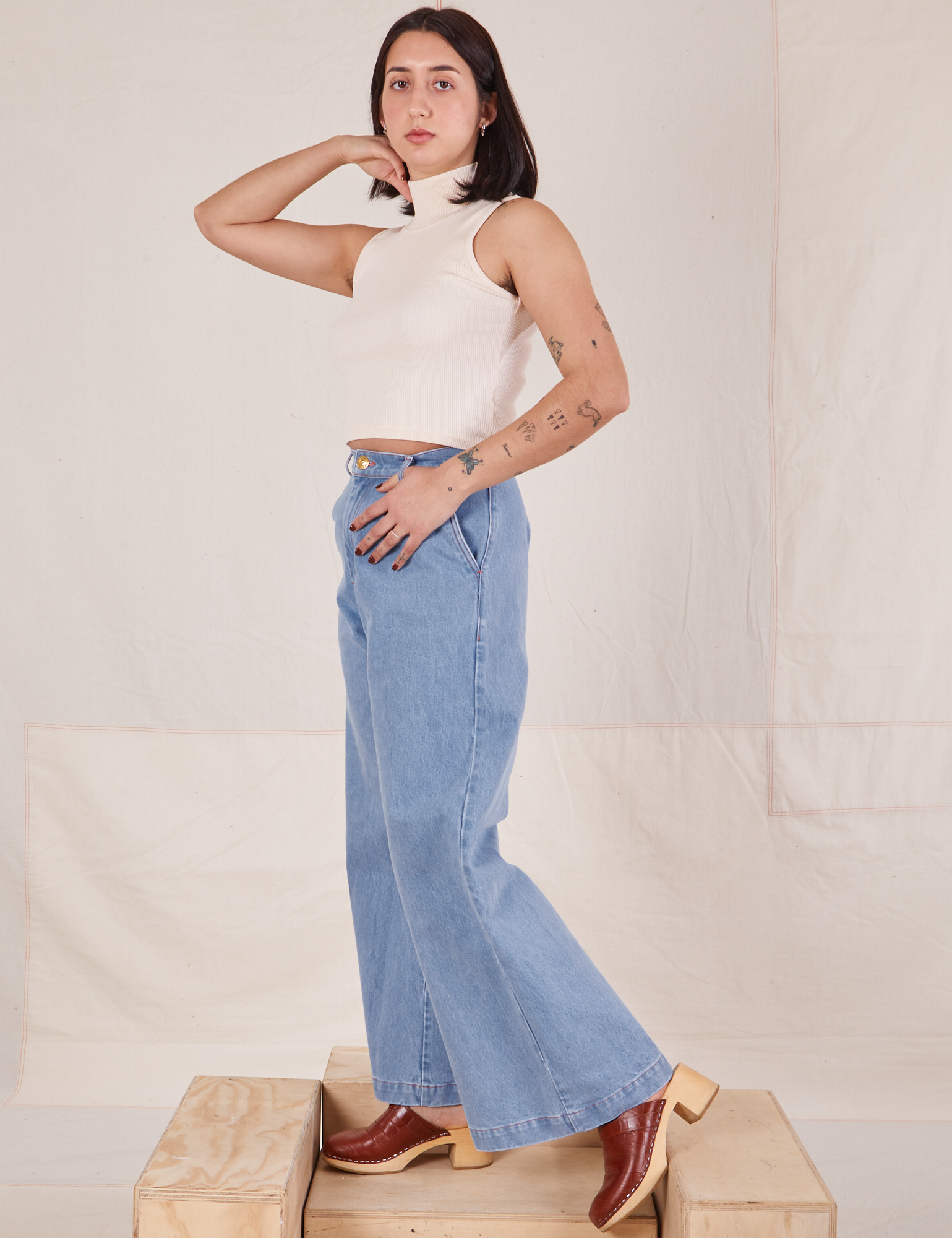 Side view of Indigo Wide Leg Trousers in Light Wash and vintage off-white Sleeveless Turtleneck
