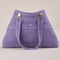 Overall Handbag in Faded Grape. Handle strap hanging down front of bag.