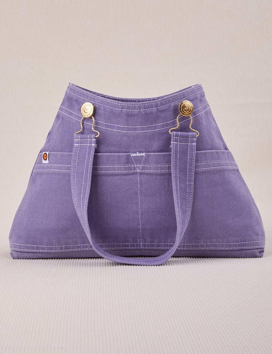 Overall Handbag in Faded Grape. Handle strap hanging down front of bag.