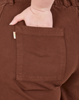 Petite Bell Bottoms in Fudgesicle Brown back pocket close up. Ashley has her hand in the pocket.