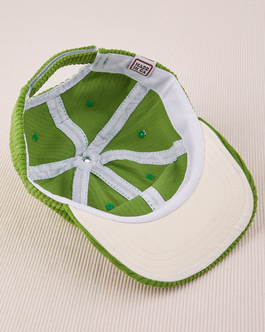 Dugout Corduroy Hat in Bright Olive flipped over. White satin under-bill