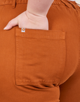 Petite Pencil Pants in Burnt Terracotta back pocket close up. Ashley has her hand in the pocket.