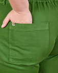 Back pocket close up of Short Sleeve Jumpsuit in Lawn Green. Marielena has her hand in the pocket.