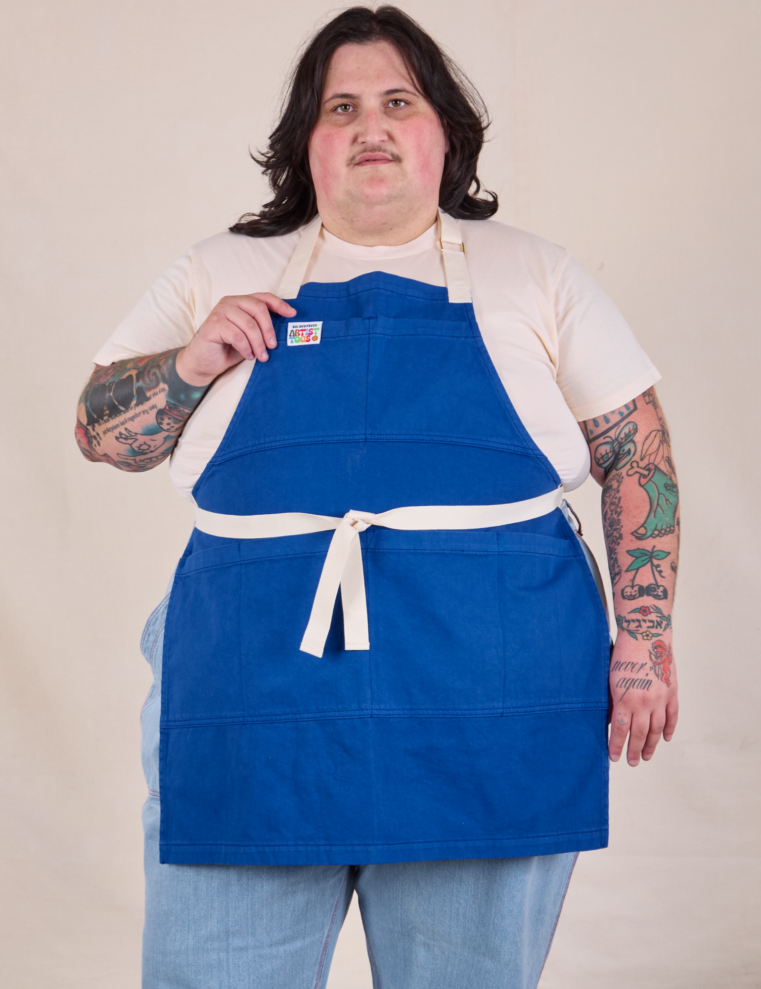 Sam is wearing Full Denim Apron in Royal Blue