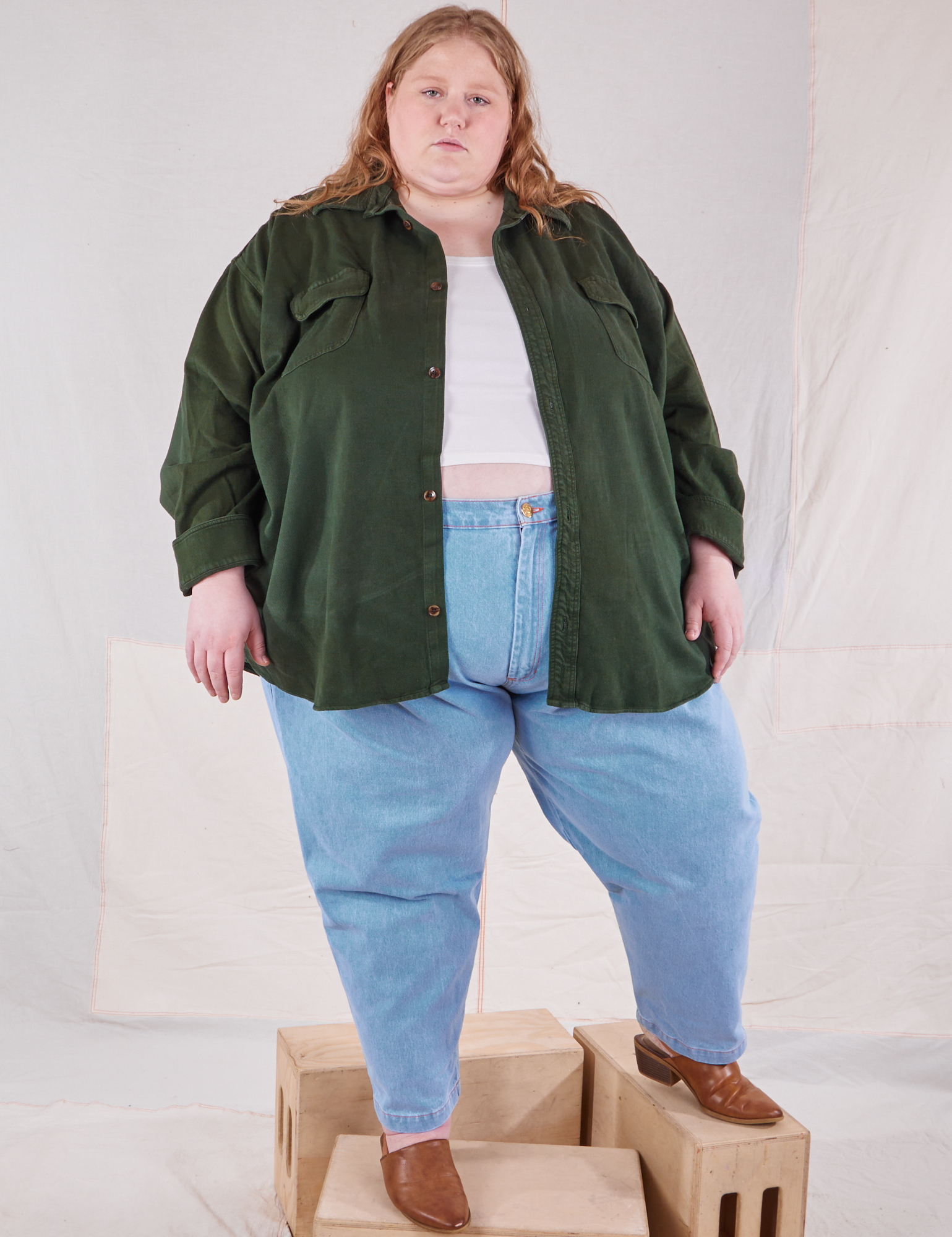 Catie is wearing Flannel Overshirt in Swamp Green, vintage off-white Cropped Tank Top and light wash Trouser Jeans