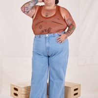 Sam is wearing Mesh Tank Top in Burnt Terracotta and light wash Sailor Jeans