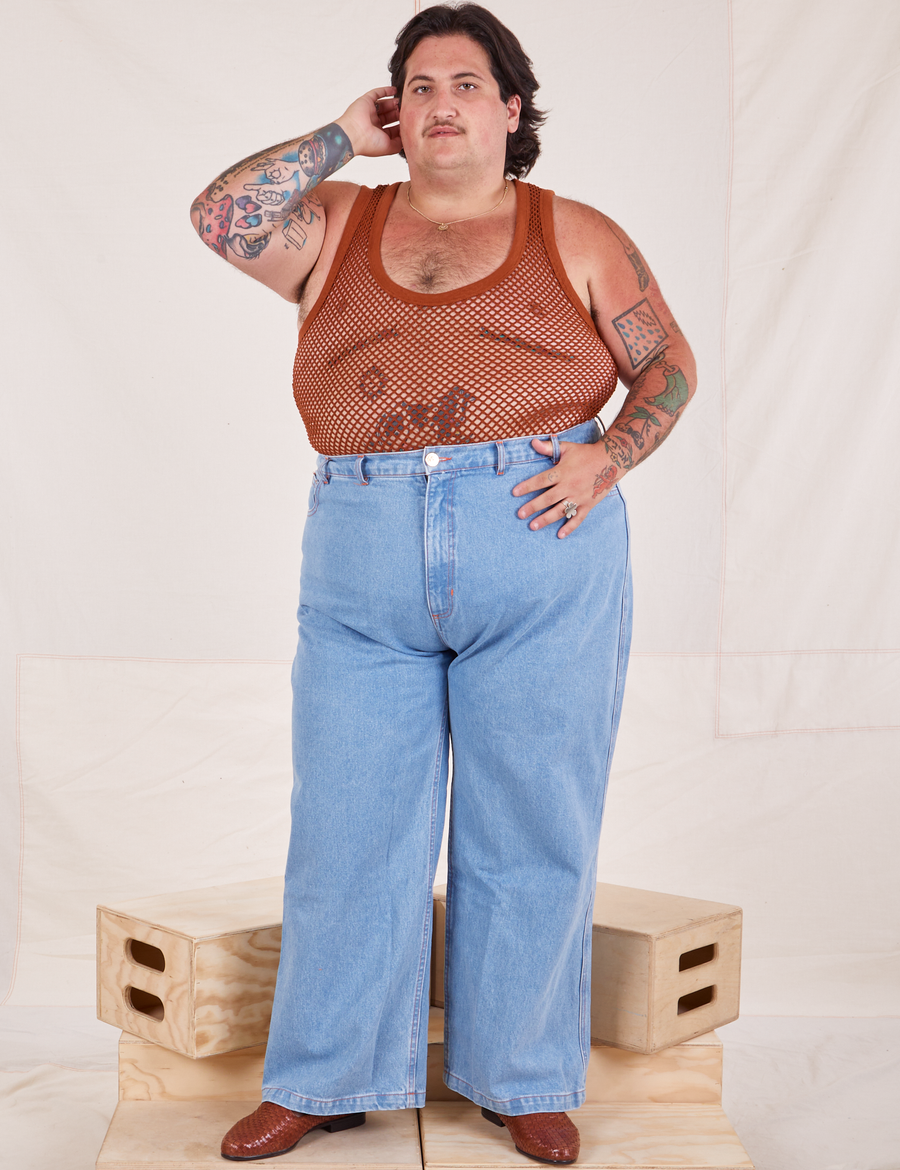 Sam is wearing Mesh Tank Top in Burnt Terracotta and light wash Sailor Jeans