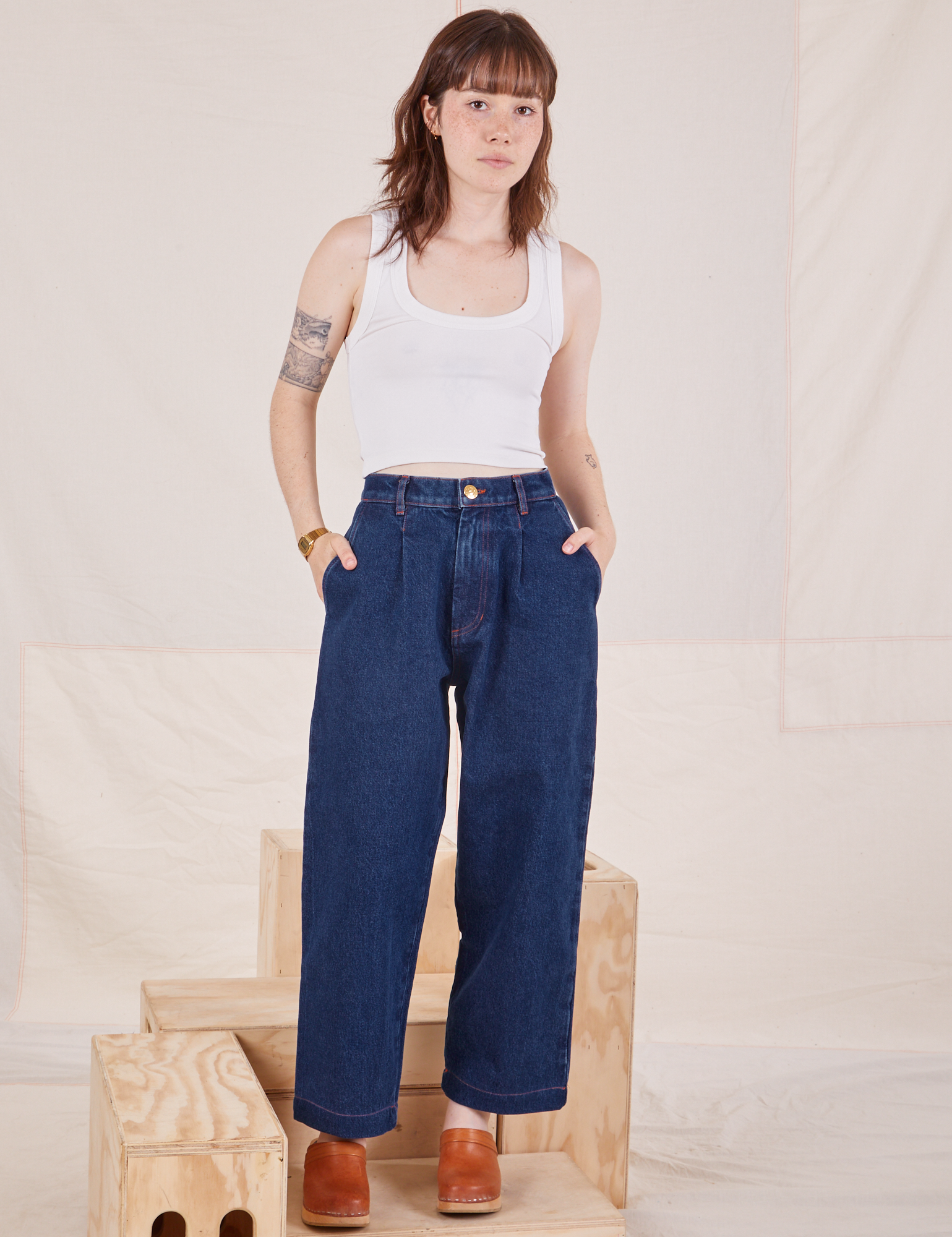Hana is 5&#39;3&quot; and wearing XXS Petite Denim Trouser Jeans in Dark Wash paired with vintage off-white Cropped Tank Top