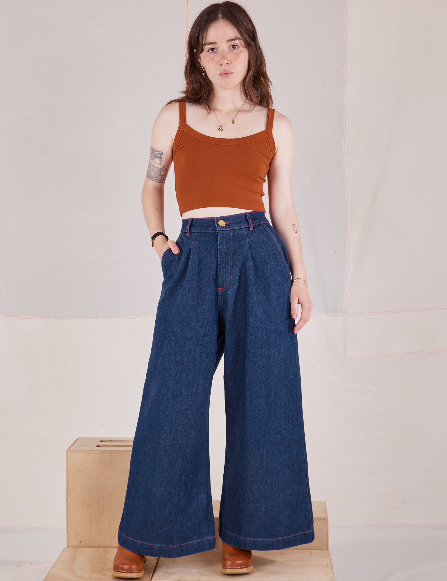 Hana is 5&#39;3&quot; and wearing P Petite Indigo Wide Leg Trousers in Dark Wash and burnt terracotta Cami