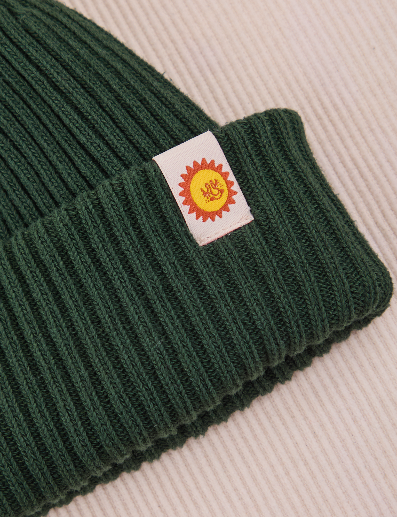 Ribbed Beanie in Swamp Green close up of sun baby tag